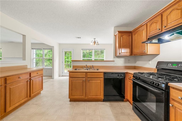 85 Old Gettysburg Way, Dallas, GA 30157 - kitchen with black appliances, under cabinet range hood, healthy amount of natural light, brown cabinets, and a textured ceiling