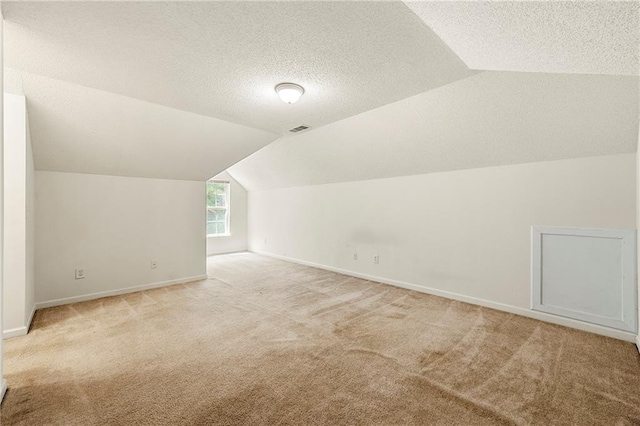 85 Old Gettysburg Way, Dallas, GA 30157 - additional living space with vaulted ceiling, light colored carpet, baseboards, and a textured ceiling