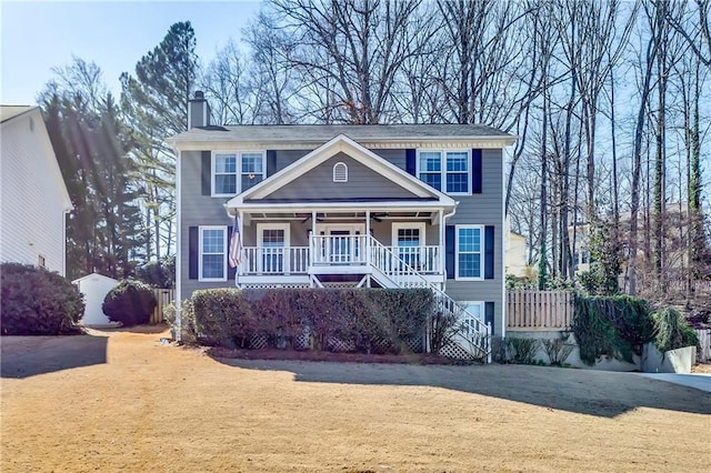 view of front of property featuring driveway, a chimney, a porch, stairs, and a front lawn