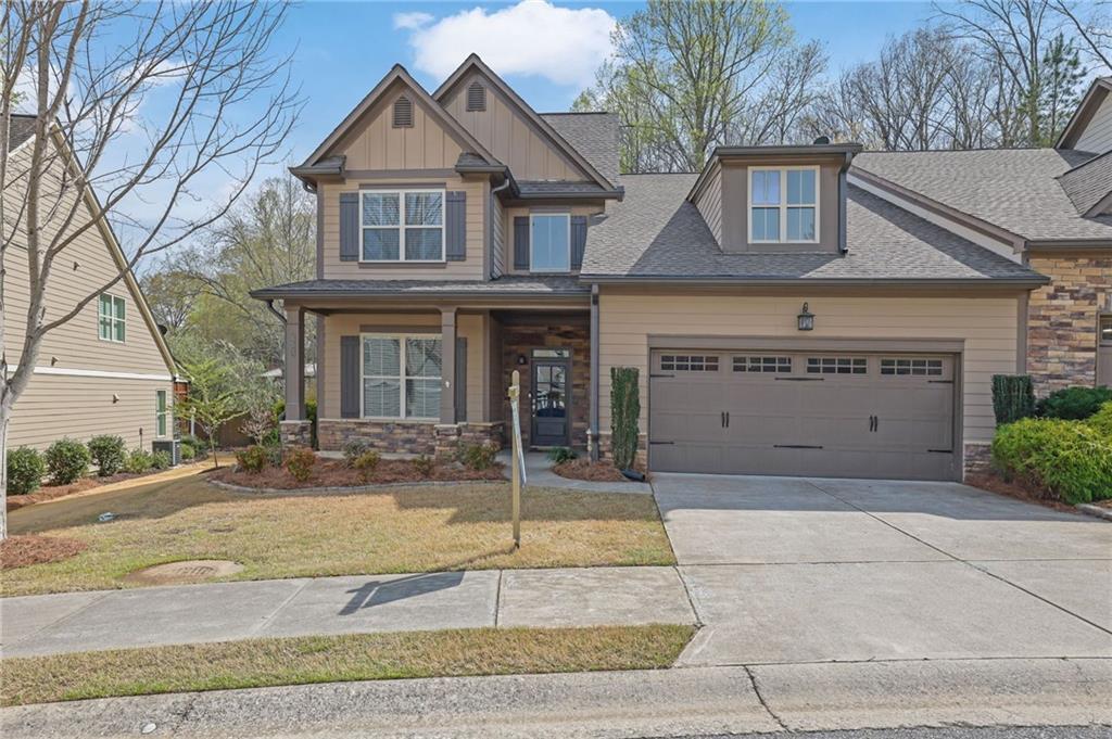 craftsman-style house with a front lawn, stone siding, a garage, and concrete driveway