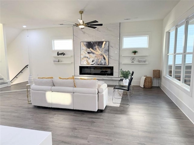 living room featuring ceiling fan, a high end fireplace, and dark hardwood / wood-style floors