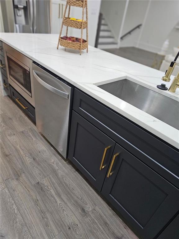 kitchen featuring light stone countertops, appliances with stainless steel finishes, sink, and light hardwood / wood-style floors