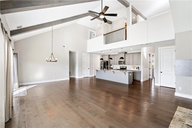 unfurnished living room featuring dark hardwood / wood-style flooring, beamed ceiling, ceiling fan with notable chandelier, and high vaulted ceiling