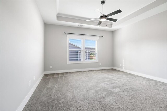 carpeted empty room featuring ceiling fan and a tray ceiling