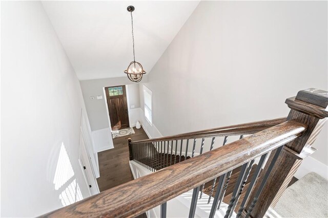 stairs featuring hardwood / wood-style flooring, vaulted ceiling, and a notable chandelier