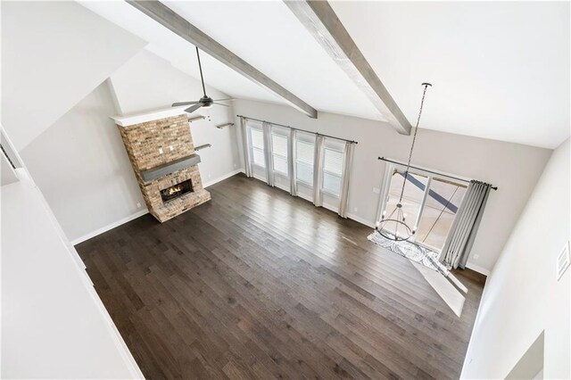 unfurnished living room with beamed ceiling, dark hardwood / wood-style flooring, a brick fireplace, and ceiling fan