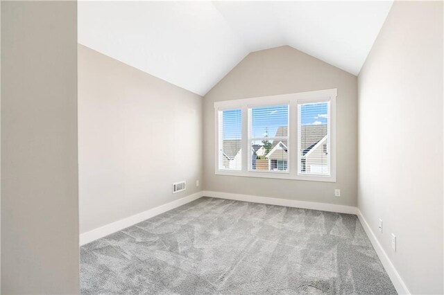 carpeted empty room with vaulted ceiling