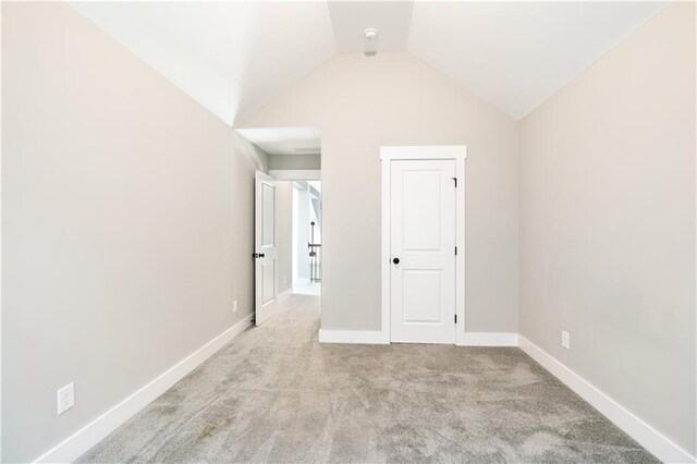 unfurnished bedroom featuring light colored carpet and vaulted ceiling