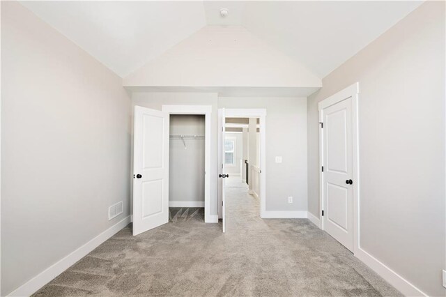 unfurnished bedroom with light colored carpet and lofted ceiling