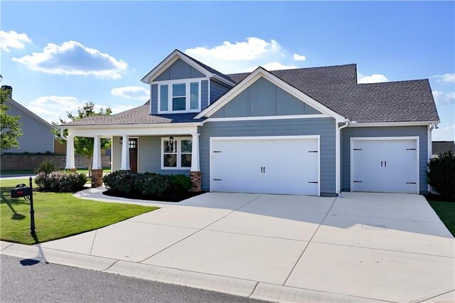 craftsman house with a front yard, a garage, and covered porch