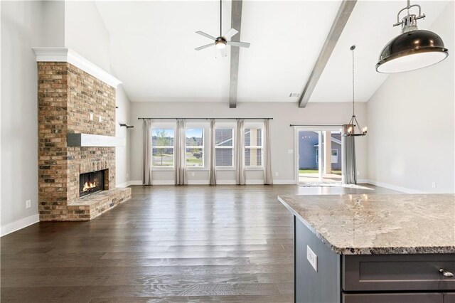 unfurnished living room with a brick fireplace, dark hardwood / wood-style flooring, beamed ceiling, high vaulted ceiling, and ceiling fan with notable chandelier