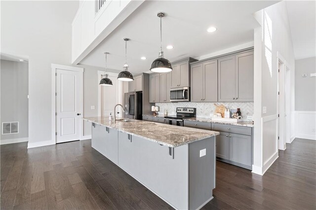 kitchen featuring a kitchen breakfast bar, gray cabinets, dark hardwood / wood-style flooring, and stainless steel appliances