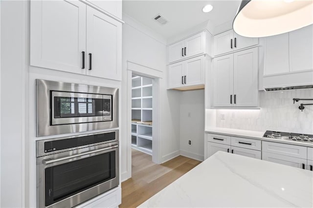 3601 Perry Smith Rd, Monroe, GA 30656 - kitchen featuring light wood-style floors, stainless steel appliances, white cabinetry, decorative backsplash, and visible vents