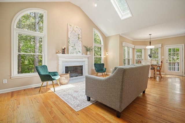 921 Laurel Crest Dr, Woodstock, GA 30189 - living area with light wood-style floors, a glass covered fireplace, baseboards, a skylight, and ornamental molding