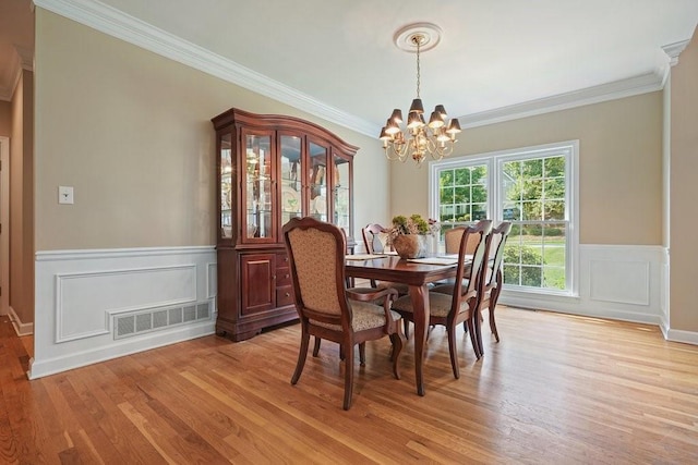 921 Laurel Crest Dr, Woodstock, GA 30189 - dining area featuring a chandelier, crown molding, light wood-style flooring, wainscoting, and a decorative wall
