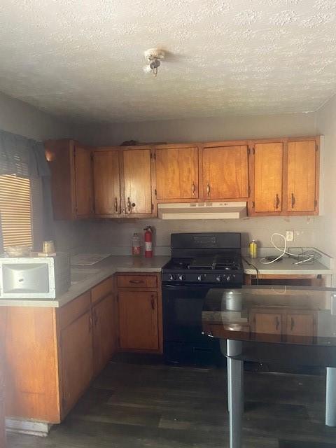 kitchen with a textured ceiling, dark hardwood / wood-style floors, and black gas range oven