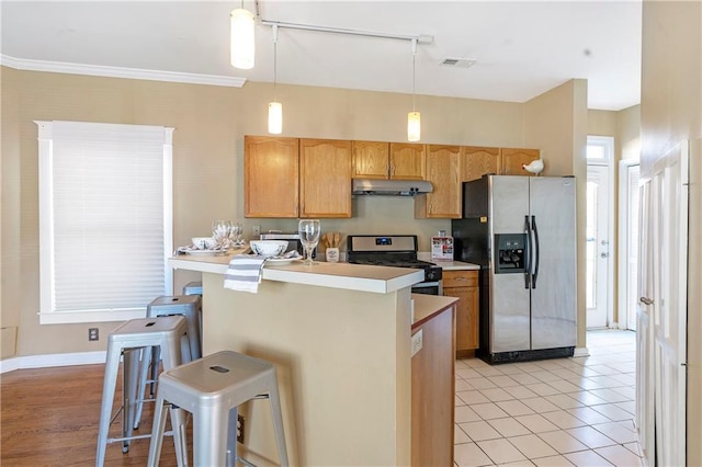 kitchen featuring hanging light fixtures, light tile patterned floors, stainless steel appliances, and a breakfast bar area