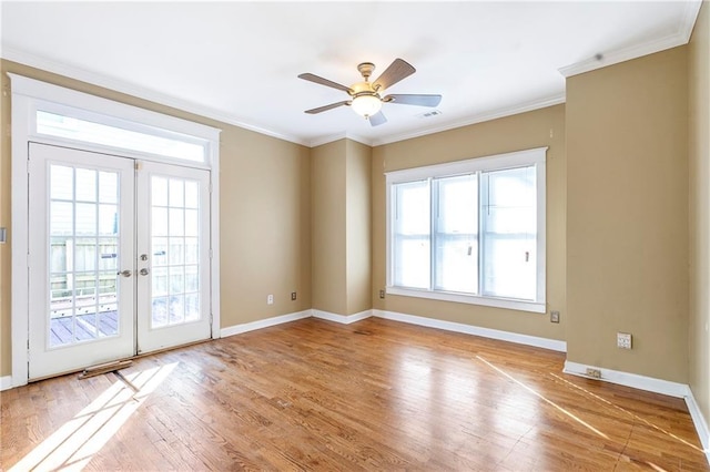 empty room with ceiling fan, plenty of natural light, crown molding, and french doors