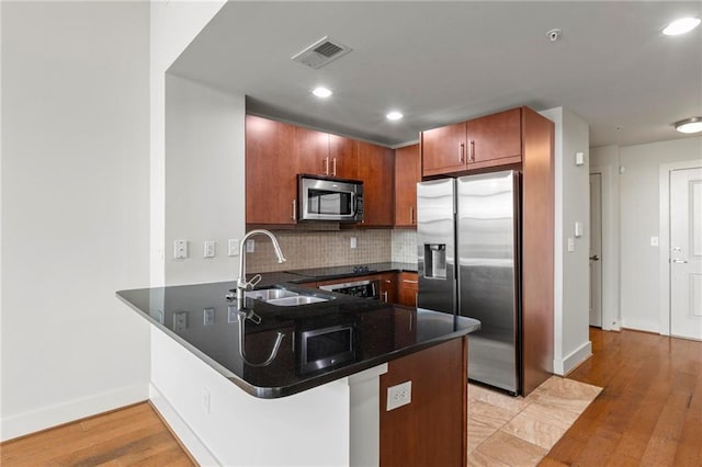 kitchen featuring appliances with stainless steel finishes, kitchen peninsula, sink, and backsplash