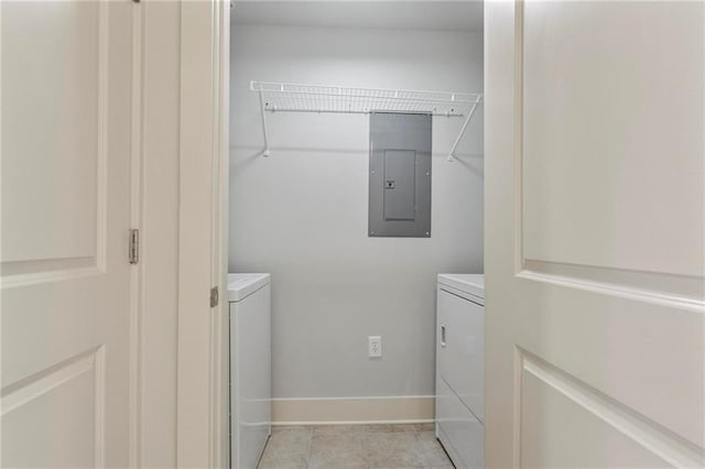 clothes washing area featuring light tile patterned flooring, washing machine and clothes dryer, and electric panel