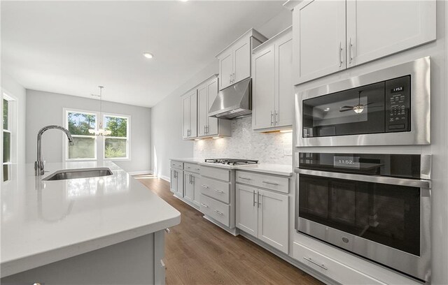 kitchen featuring built in microwave, sink, decorative light fixtures, decorative backsplash, and white cabinets