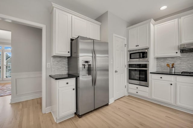 kitchen with stainless steel appliances, dark countertops, and white cabinetry