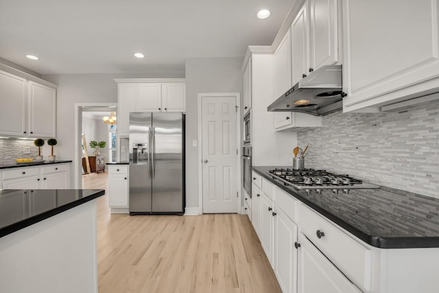 kitchen featuring dark countertops, under cabinet range hood, white cabinetry, and appliances with stainless steel finishes