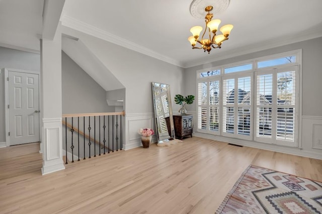 interior space featuring visible vents, wainscoting, ornamental molding, wood finished floors, and a notable chandelier