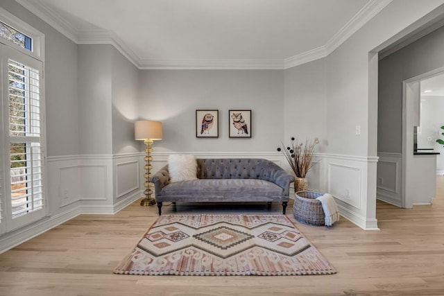 living area with a wainscoted wall, ornamental molding, and wood finished floors