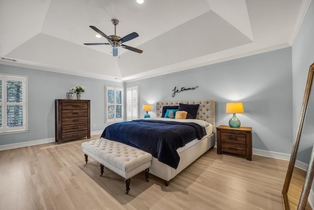 bedroom with a tray ceiling, baseboards, and light wood finished floors