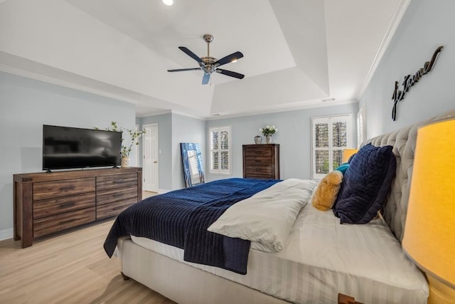 bedroom with baseboards, a ceiling fan, ornamental molding, wood finished floors, and a tray ceiling