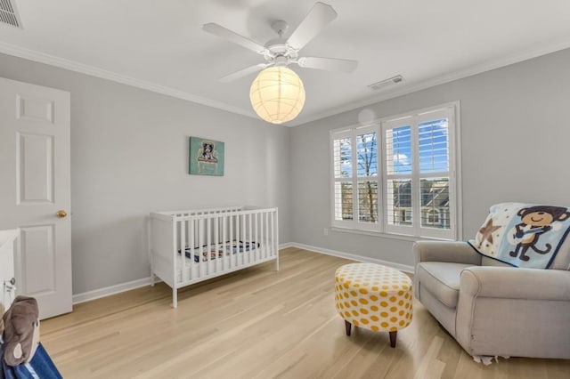 bedroom with baseboards, visible vents, crown molding, and wood finished floors