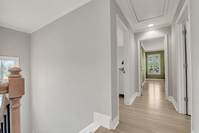 corridor featuring attic access, ornamental molding, light wood-style flooring, and baseboards