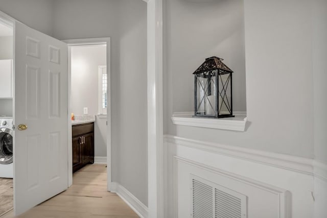 hallway featuring light wood-type flooring, washer / clothes dryer, and baseboards