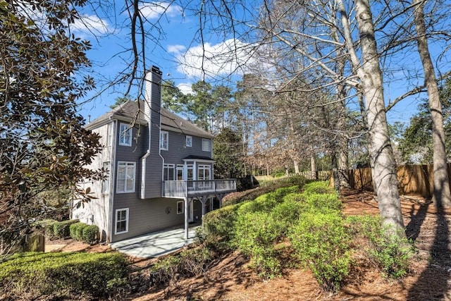 rear view of property with a patio area, a chimney, fence, and a wooden deck