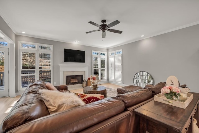 living room featuring a fireplace with flush hearth, recessed lighting, ornamental molding, and ceiling fan