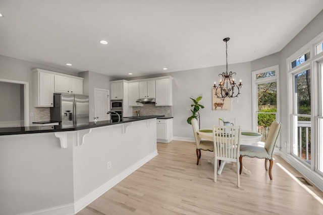 kitchen featuring stainless steel appliances, a breakfast bar, dark countertops, and white cabinetry