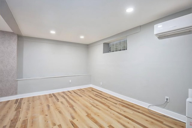 basement featuring a wall mounted AC and light hardwood / wood-style floors