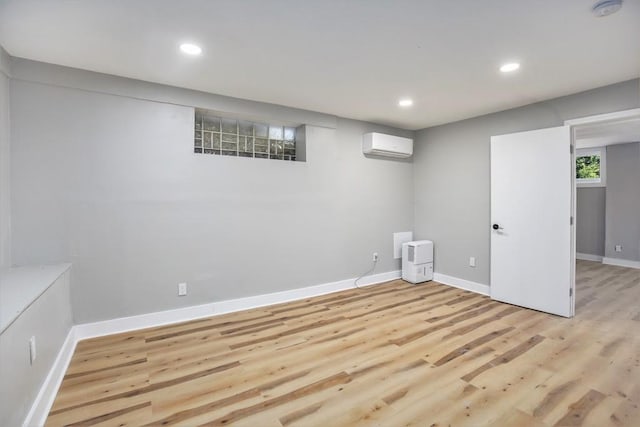 basement featuring light hardwood / wood-style floors and an AC wall unit