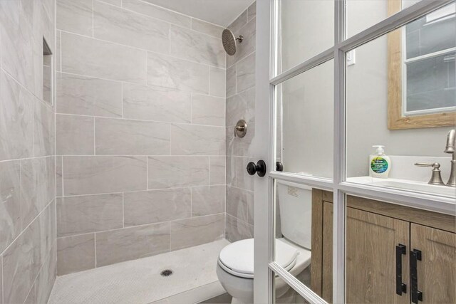 bathroom with vanity, toilet, and tiled shower