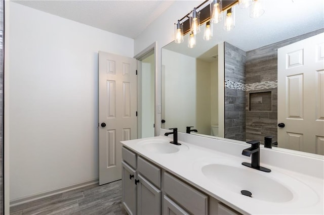 3260 Ridgefair Dr, Cumming, GA 30040 - bathroom featuring wood finished floors, double vanity, toilet, tiled shower, and baseboards