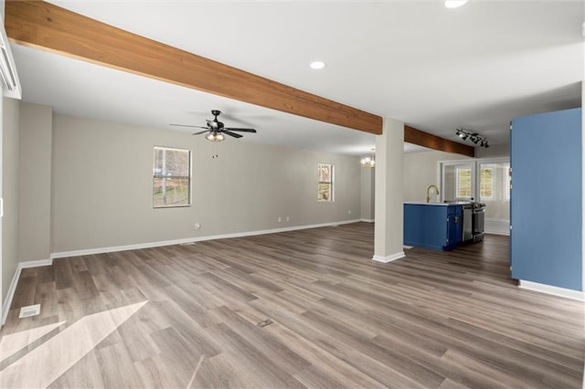 unfurnished living room featuring baseboards, beam ceiling, recessed lighting, ceiling fan with notable chandelier, and wood finished floors