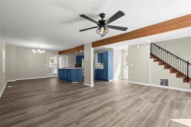 unfurnished living room with visible vents, baseboards, stairs, beam ceiling, and dark wood-style floors