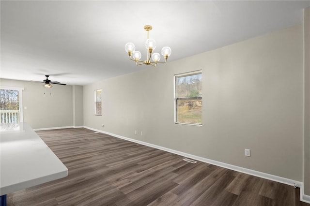 empty room featuring dark wood finished floors, visible vents, ceiling fan with notable chandelier, and baseboards