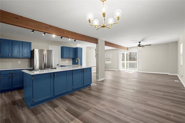 kitchen featuring blue cabinetry, beamed ceiling, light countertops, and freestanding refrigerator