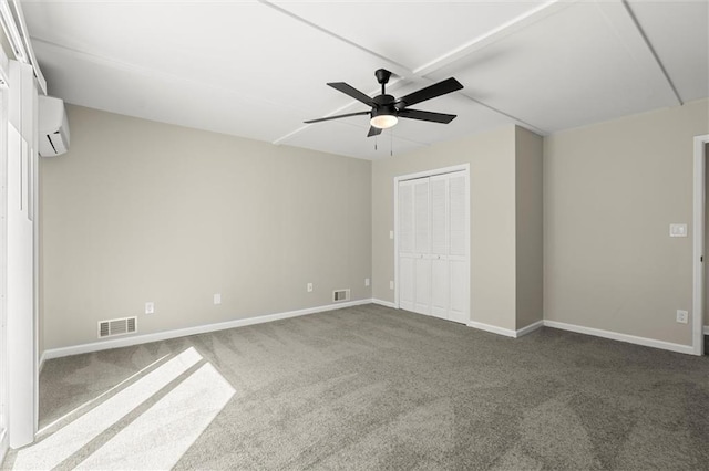 unfurnished bedroom with visible vents, carpet flooring, a wall mounted AC, and baseboards