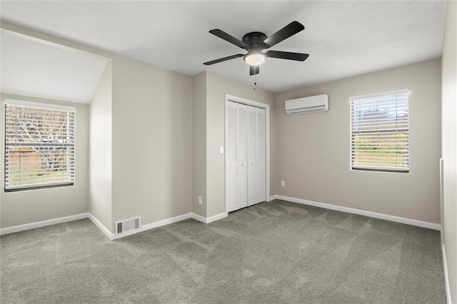 unfurnished bedroom with carpet, visible vents, baseboards, an AC wall unit, and a closet