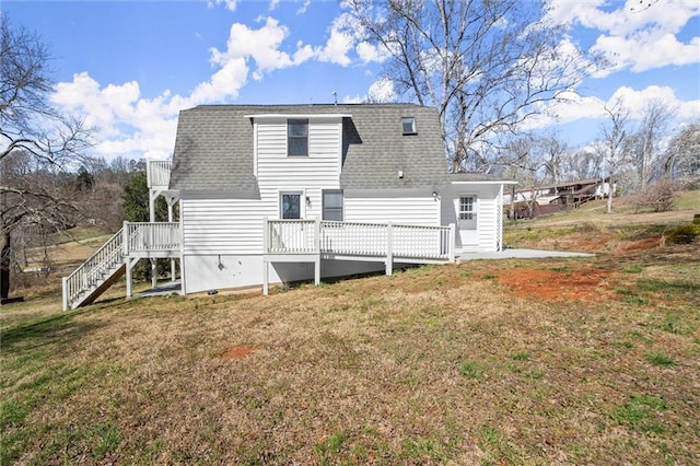 rear view of property featuring a deck, a yard, stairs, and roof with shingles