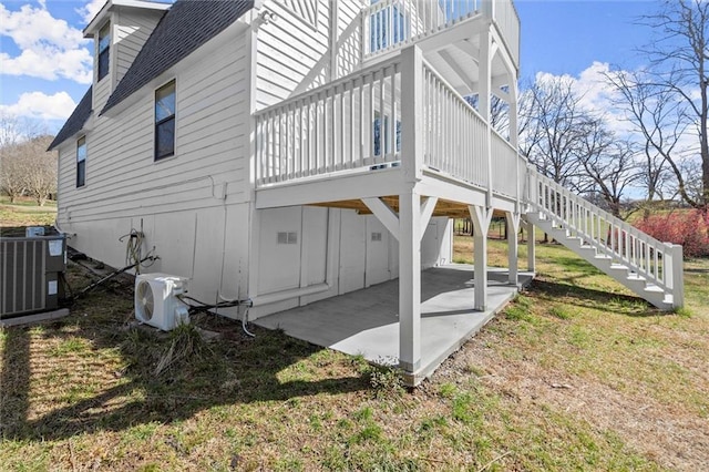 view of home's exterior featuring a patio, cooling unit, a shingled roof, stairs, and ac unit