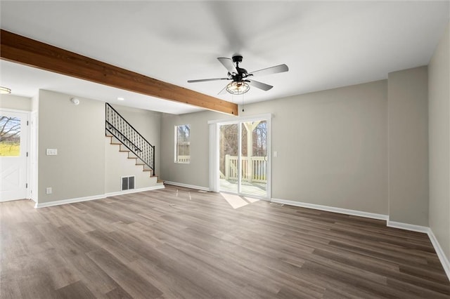 unfurnished living room featuring visible vents, beam ceiling, wood finished floors, and stairs